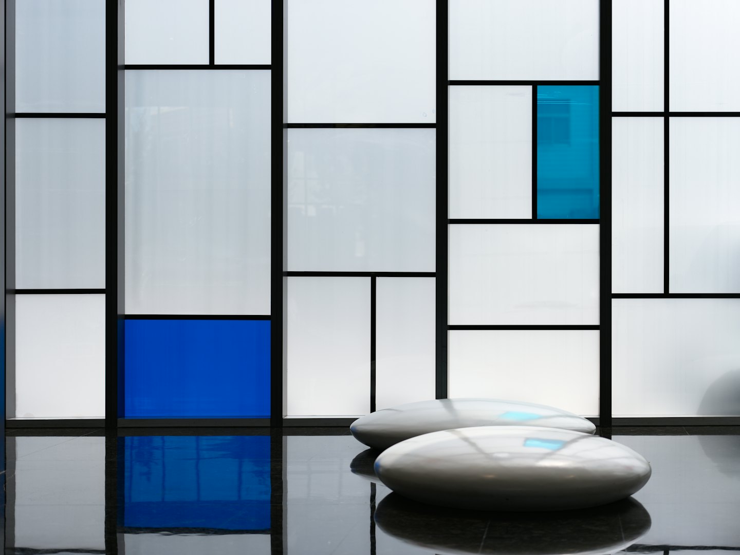 Two grey benches sit before a geometric wall of panels.